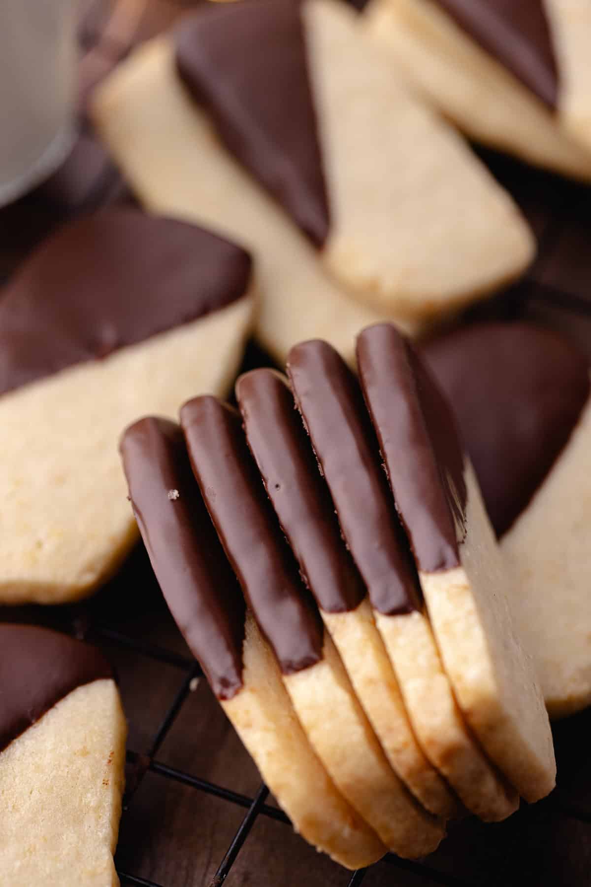 Macadamia nut shortbread also known as, hawaiian shortbread cookies are dipped in chocolate and sitting on a wire rack.