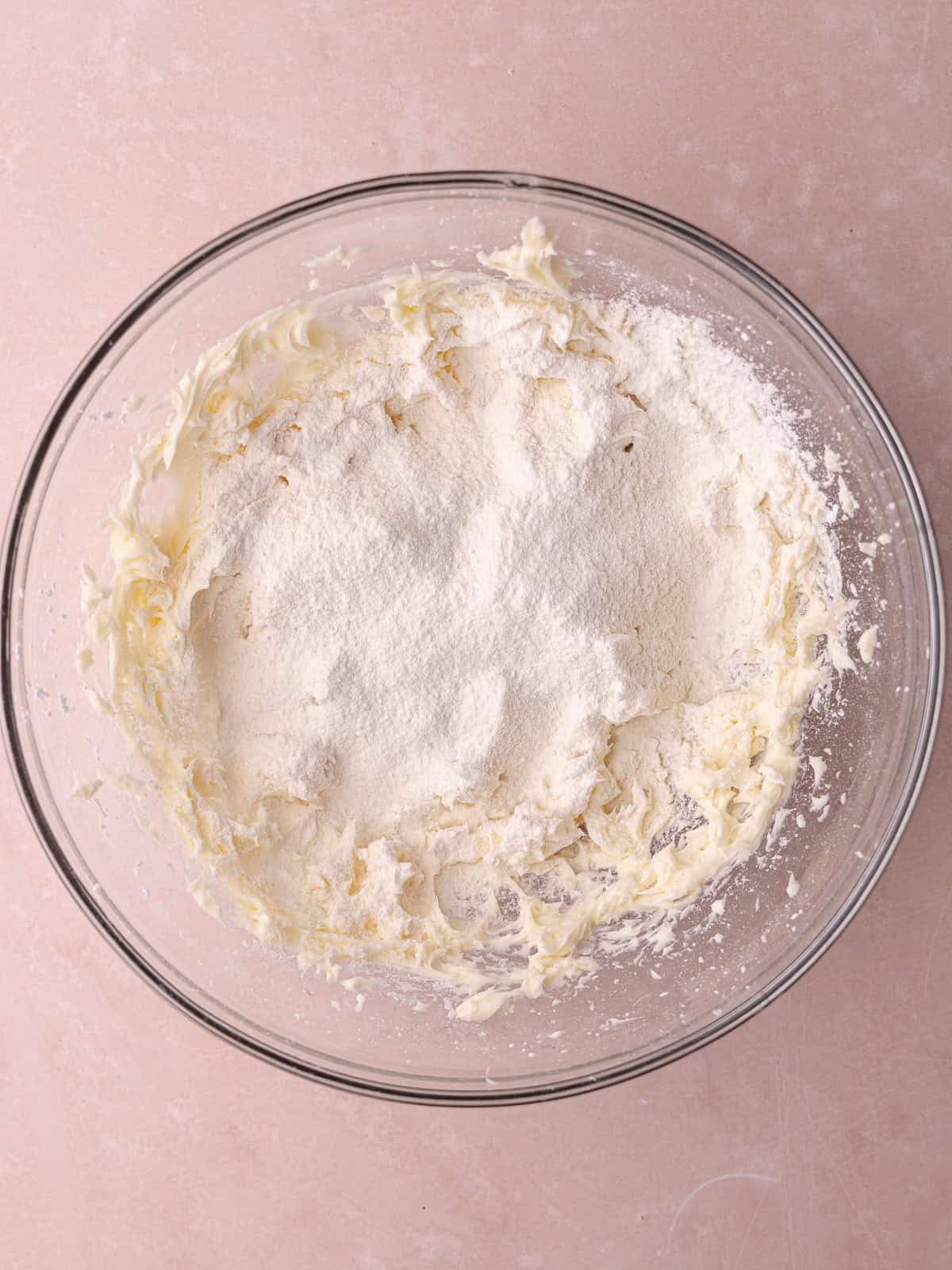 All-purpose flour is sifted into the bowl with the whipped butter mixture.