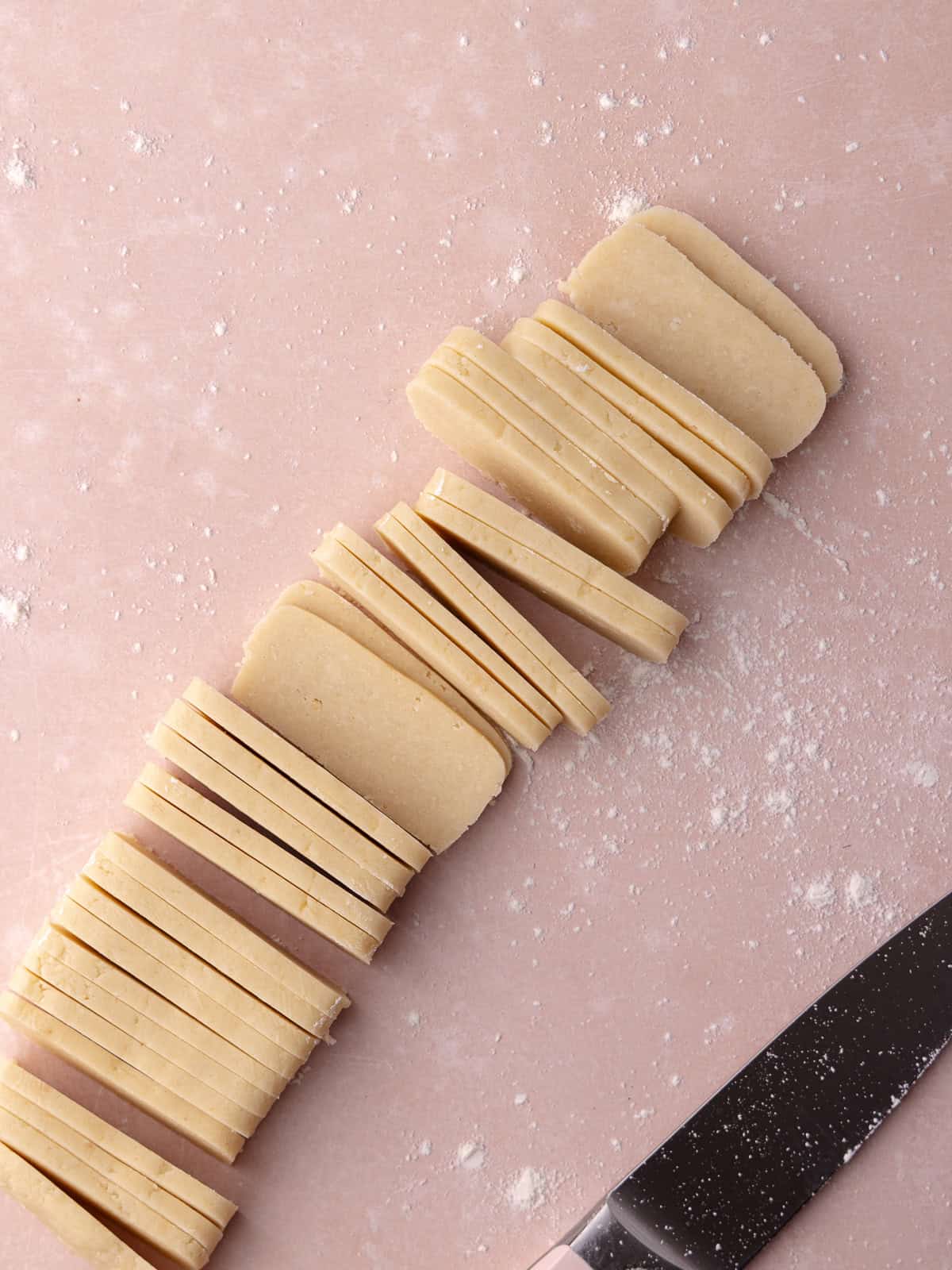 Hawaiian macadamia nut shortbread cookie dough sliced with a sharp knife.