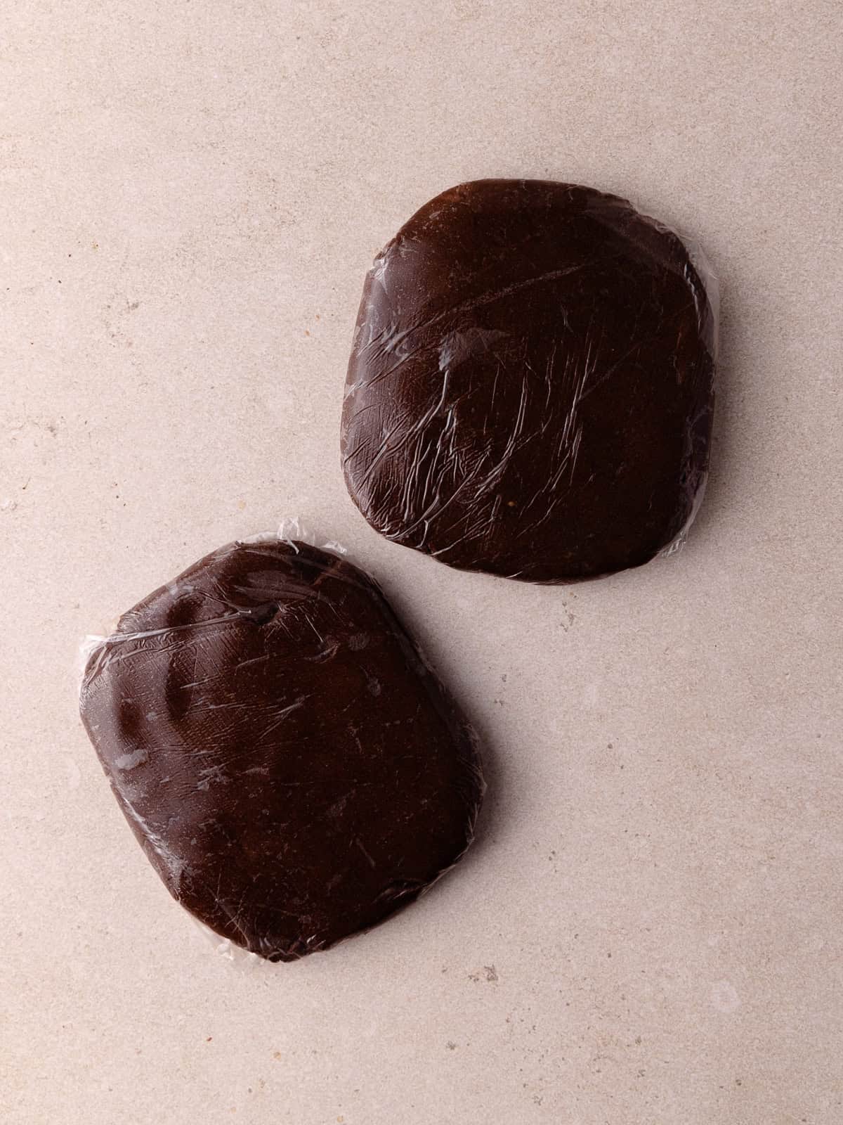 Chocolate shortbread cookie dough is divided into 2 equal discs.