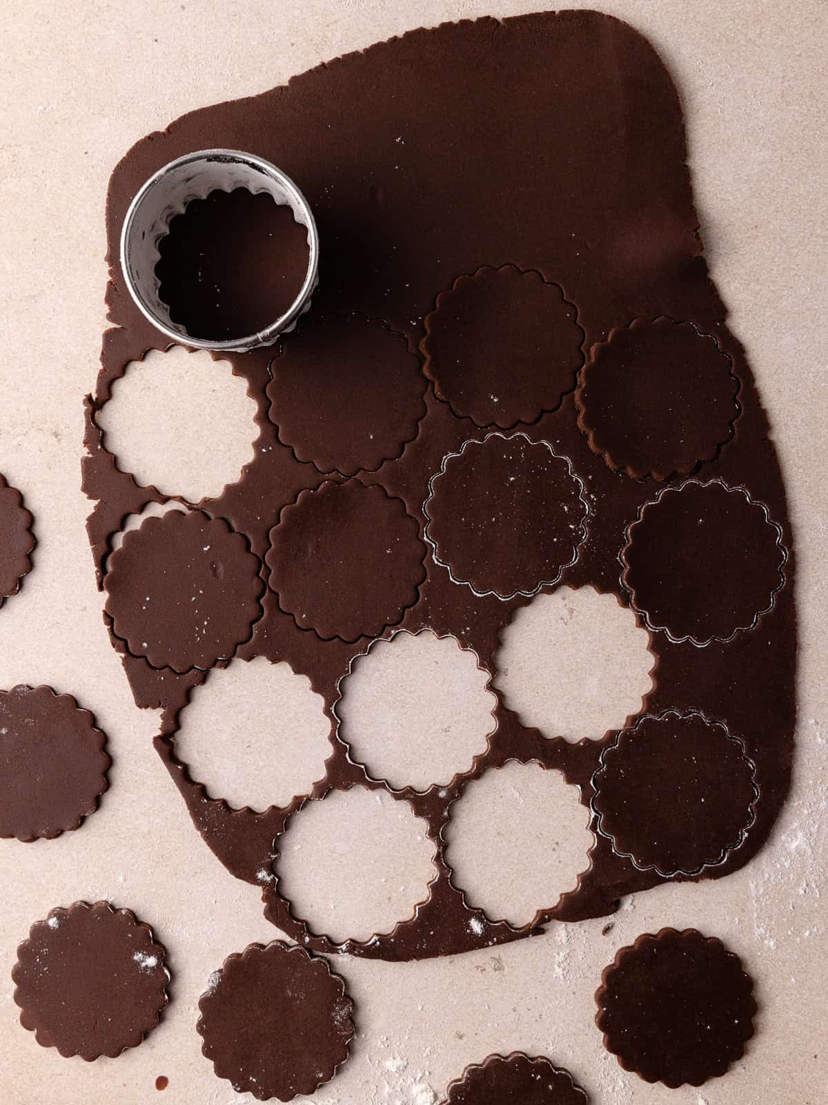 Chocolate linzer cookies are cut out on a work surface.