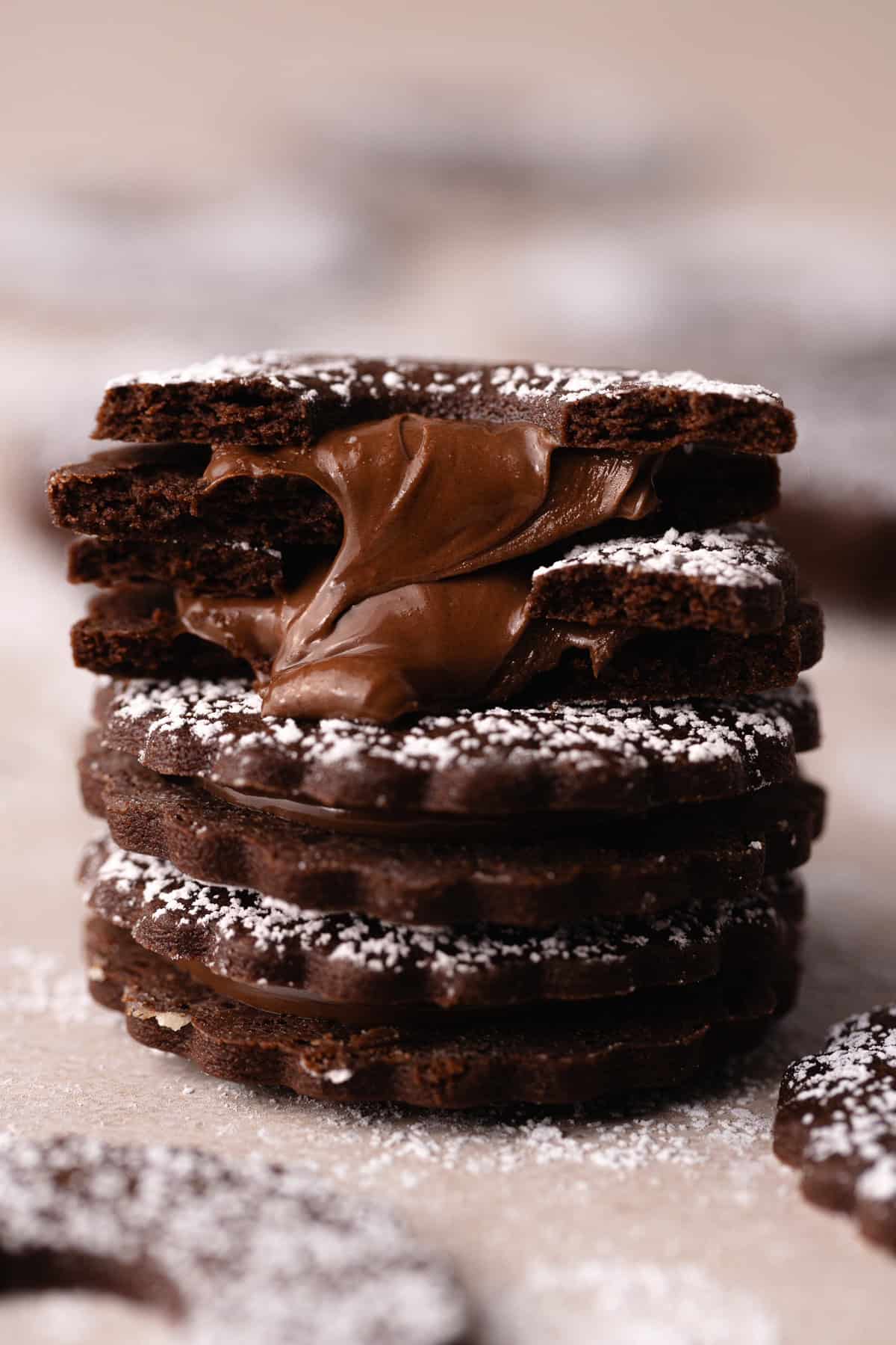 A stack of Nutella linzer sandwich cookies are dusted with powdered sugar and filled with Nutella.