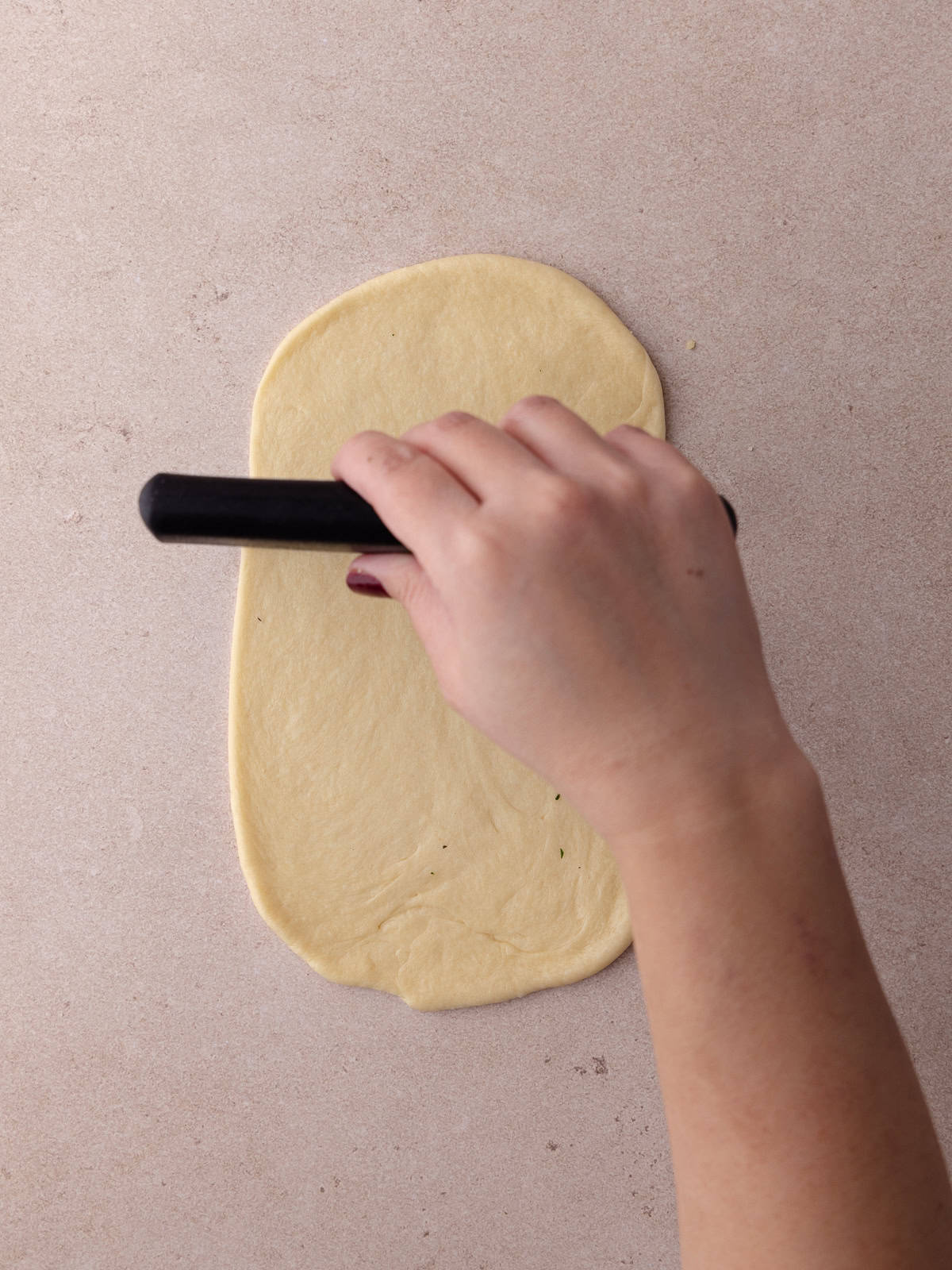 The piece of dough is scored with a bench scraper.