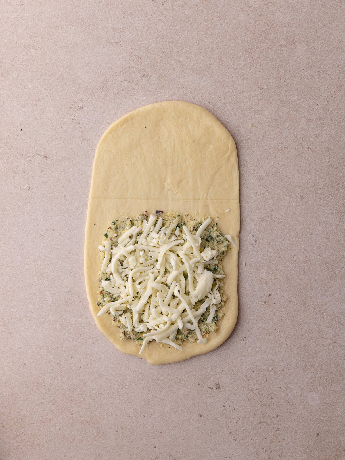 The butter garlic herb mixture is spread on to the dough and topped with shredded mozzarella cheese.