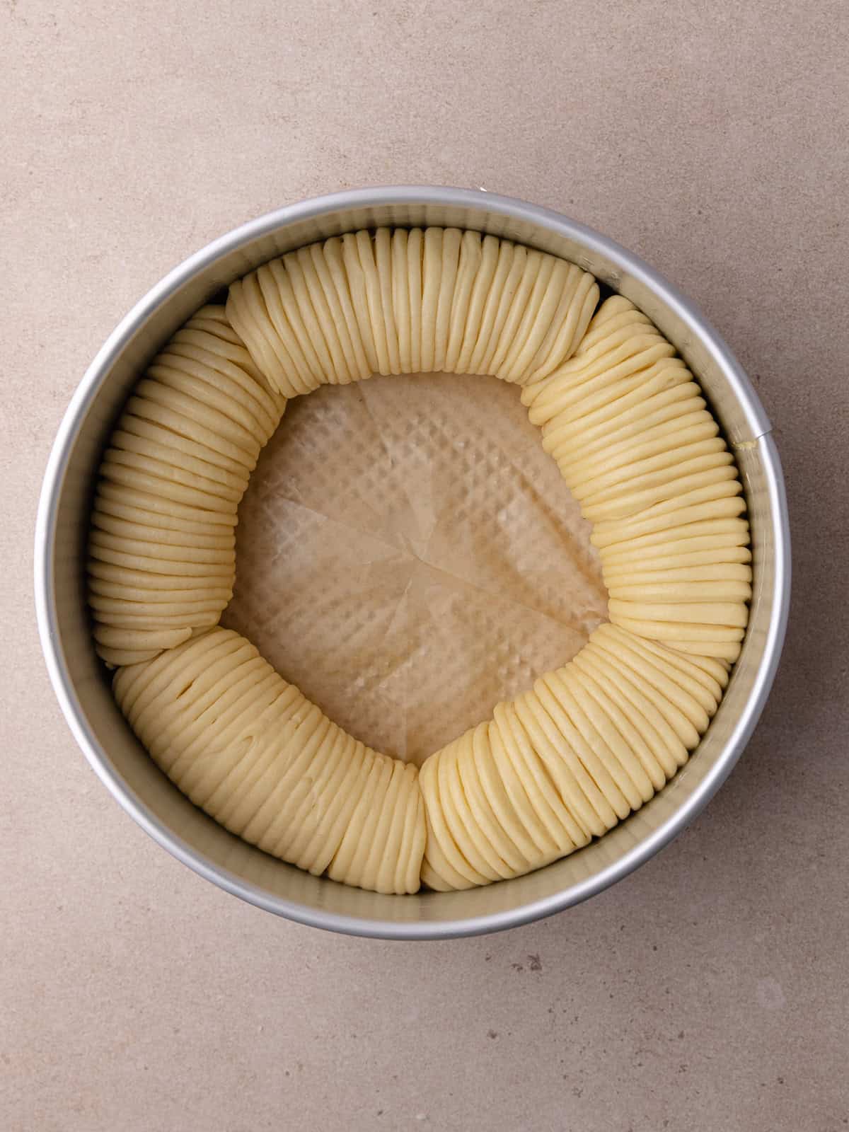 Filled tangzhong wool bread is assembled and sitting in a buttered springform pan.