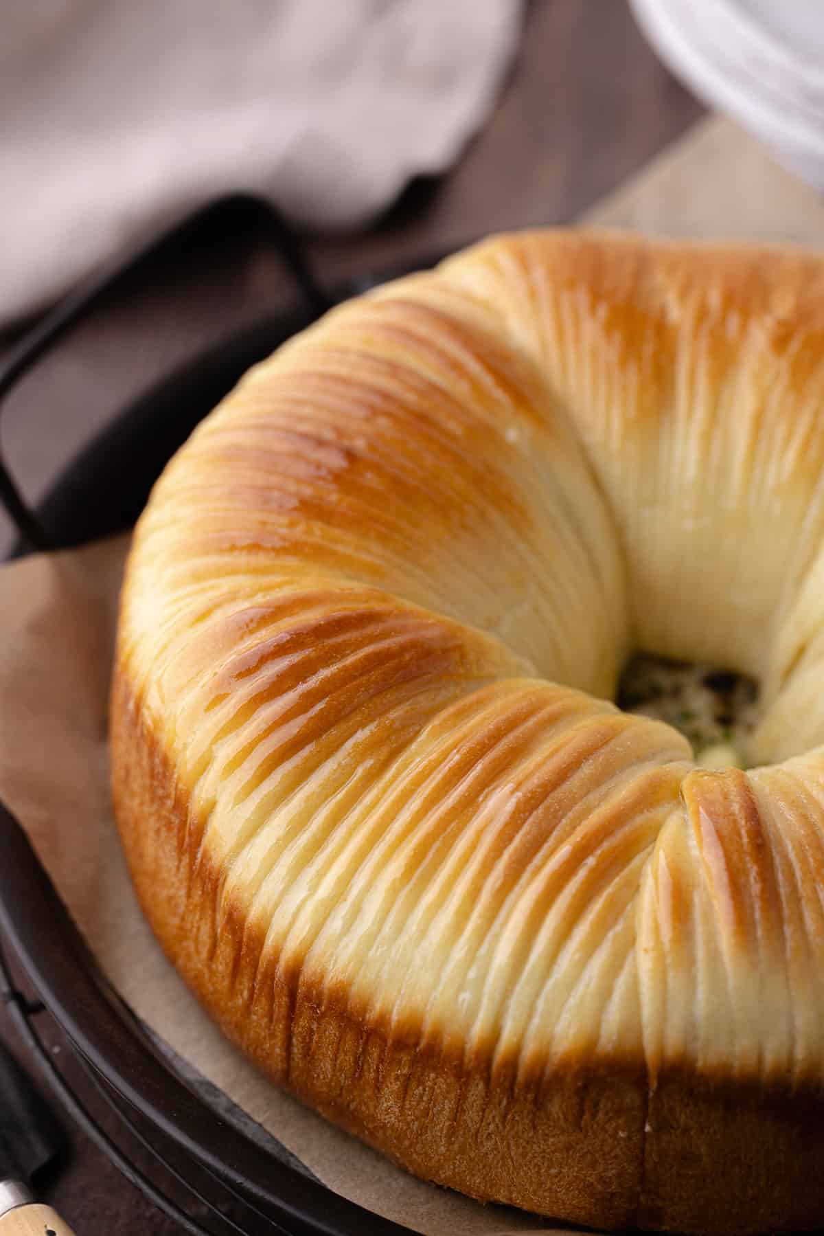 A close up of the savory wool bread with garlic, herbs and cheese sitting on a serving tray.