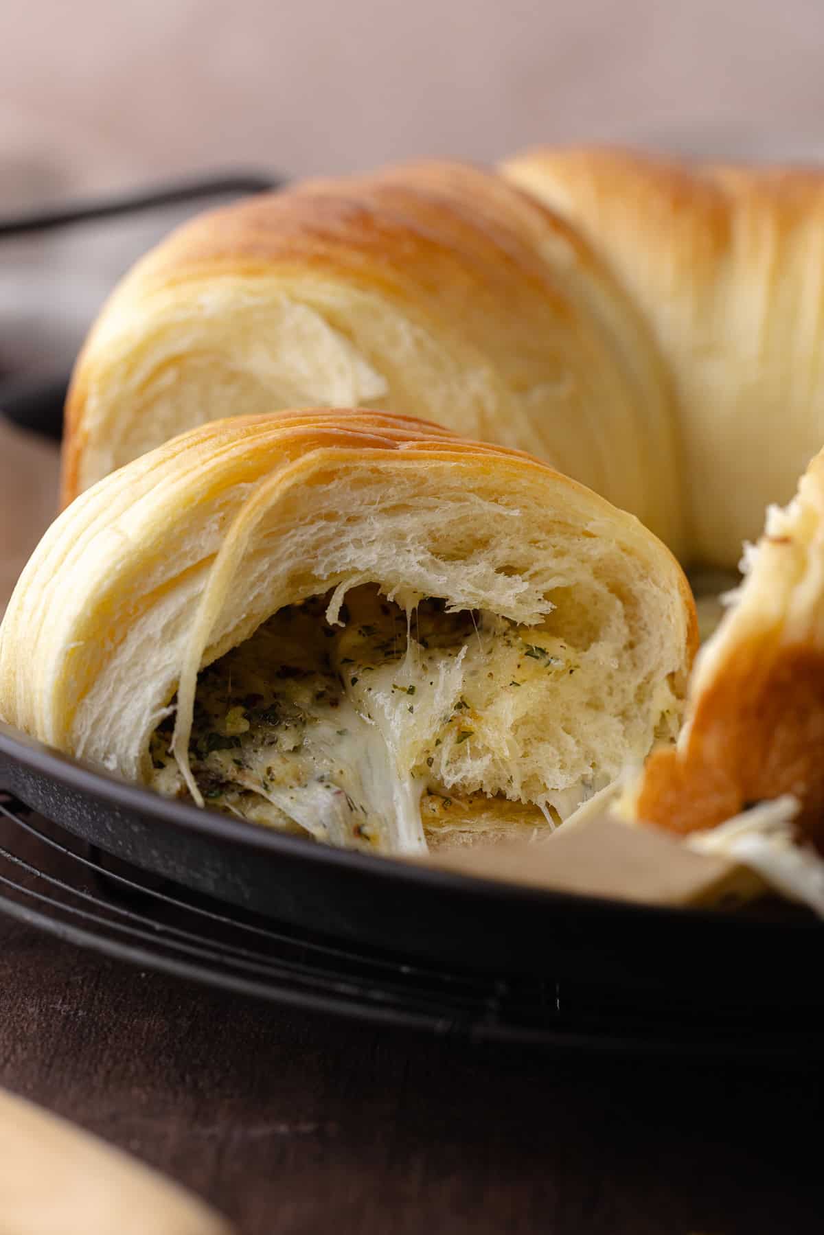 Close up of the inside of the savory wool bread shows garlic, herbs and cheese in the center of the bread. Texture is ultra soft and fluffy.