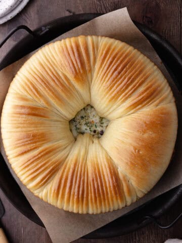 Savory wool bread with garlic, herbs and cheese sitting on a serving platter feature photo.