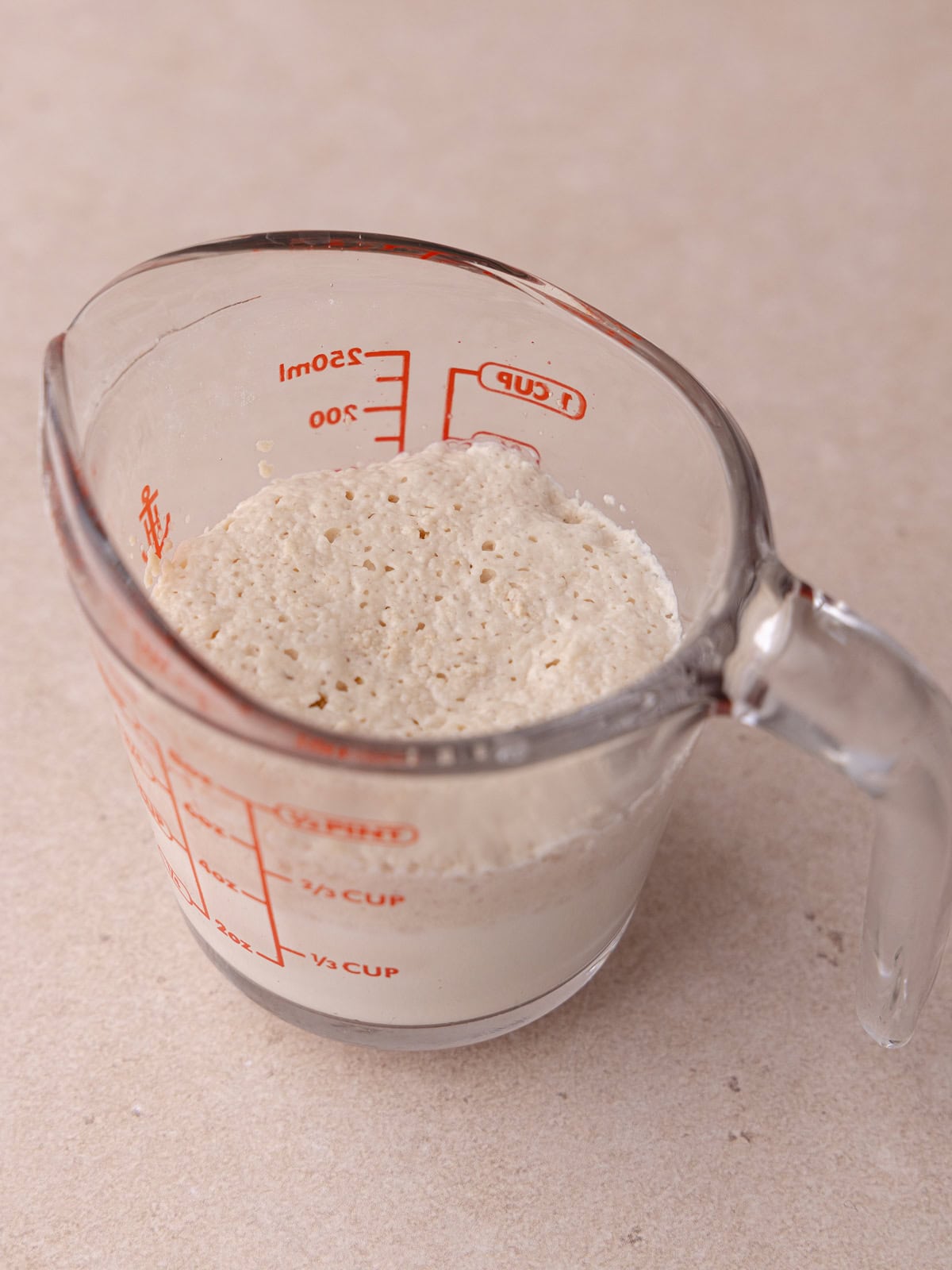 Yeast mixture in a measuring glass is bloomed and frothy.