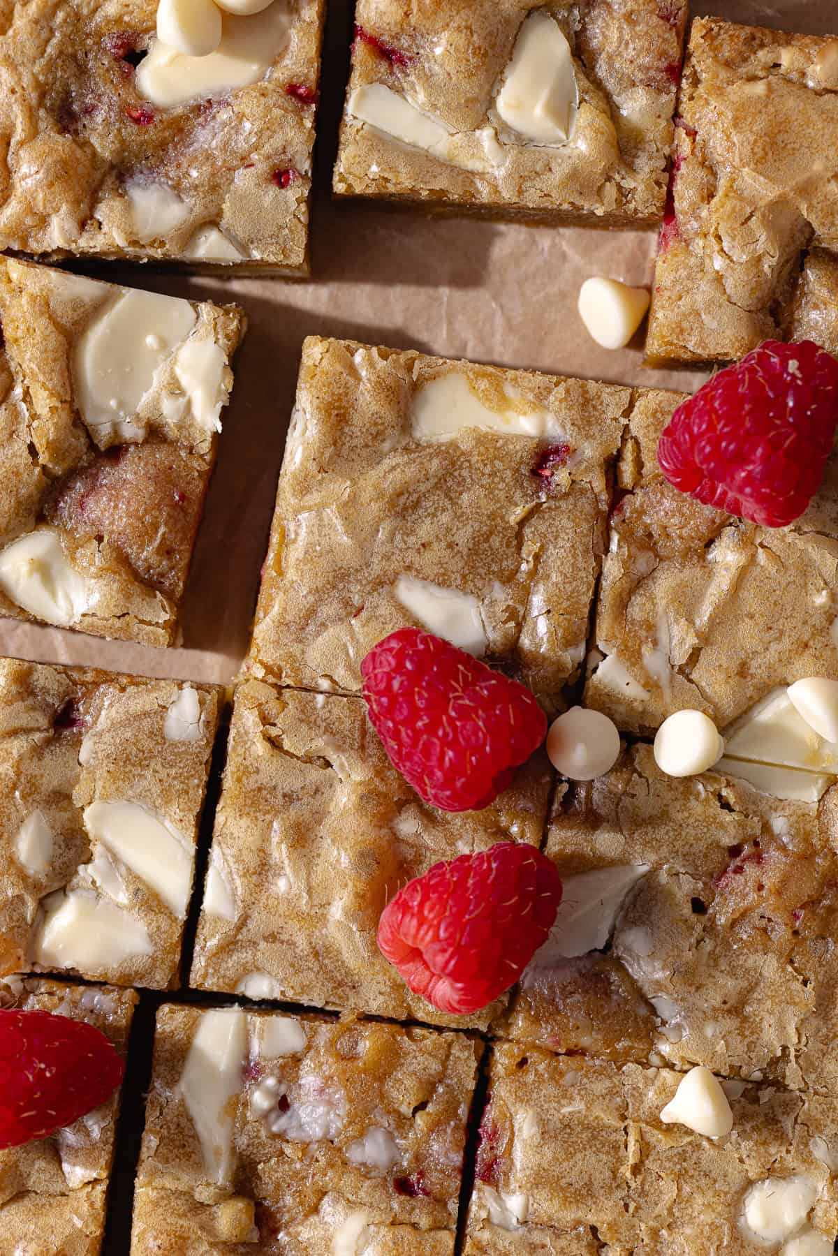 Gooey and fudgy brown butter white chocolate and raspberry blondies are cut into small squares.