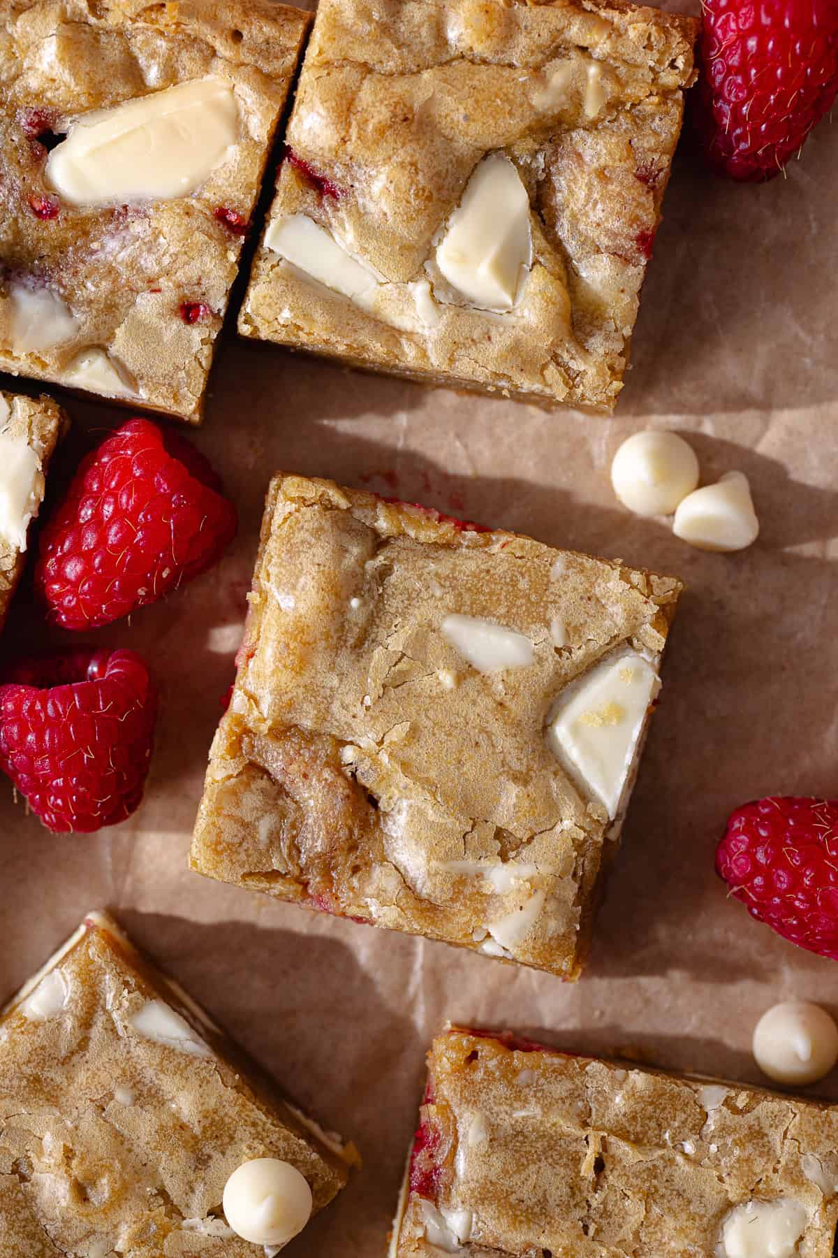 Gooey and fudgy brown butter raspberry and white chocolate blondies are cut into small squares.