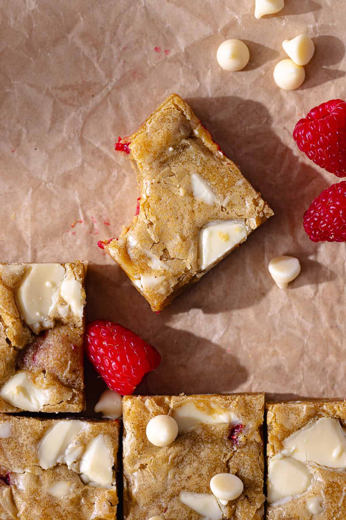 Gooey and fudgy brown butter white chocolate and raspberry blondies are cut into small squares.