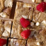 Gooey and fudgy brown butter raspberry and white chocolate blondies are cut into small squares, feature photo.