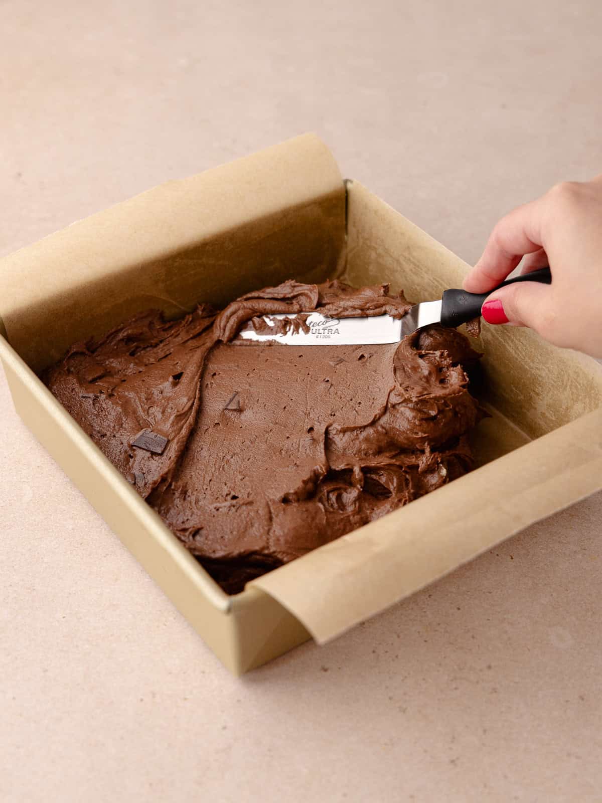 The chocolate coffee cake batter is being spread in a 8x8 inch square baking pan.