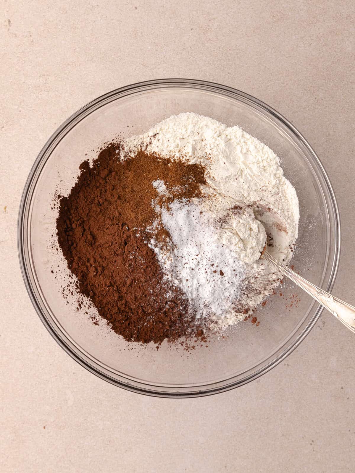 Dry ingredients which include, all-purpose flour, unsweetened cocoa powder, espresso powder, baking powder, baking soda and salt are in a medium glass mixing bowl.