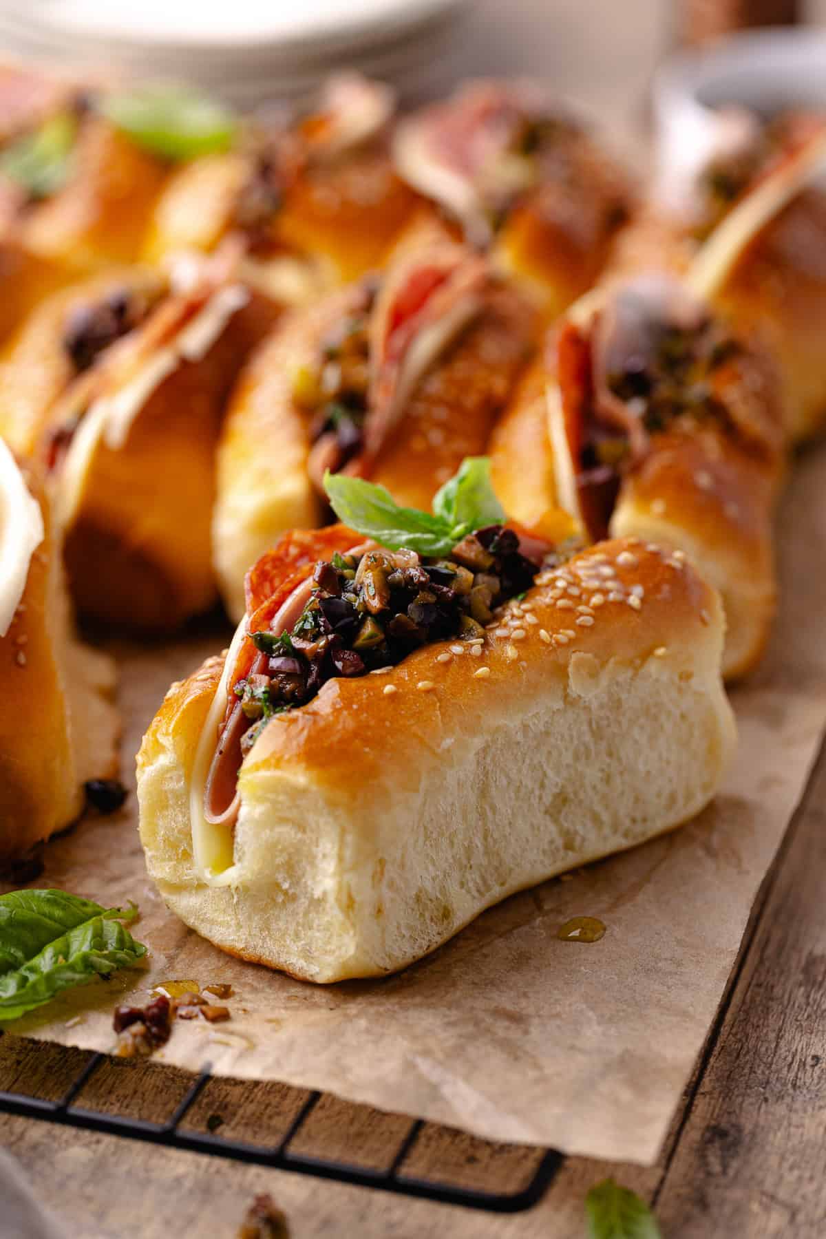 Close up of mini Italian sandwiches made with homemade mini brioche rolls and topped with olive tapenade.