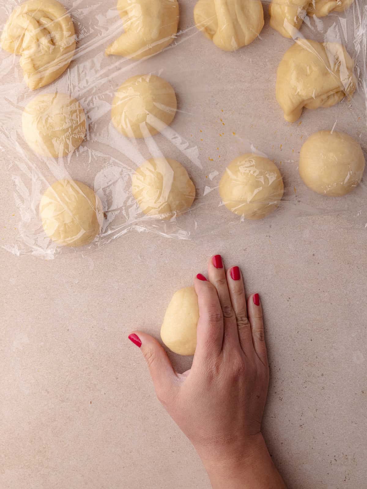 The ball of dough is shaped on the work surface to smooth out the surface.