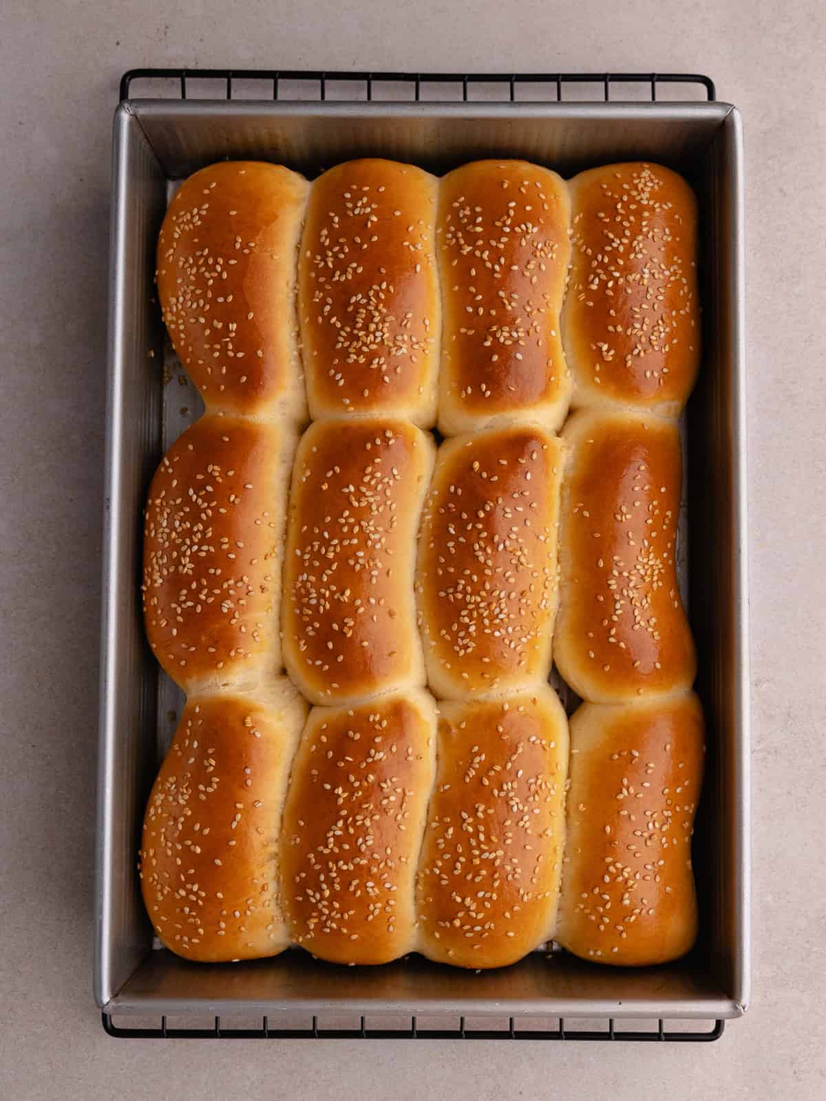 Mini brioche buns are baked until golden brown and sitting in a baking tray.