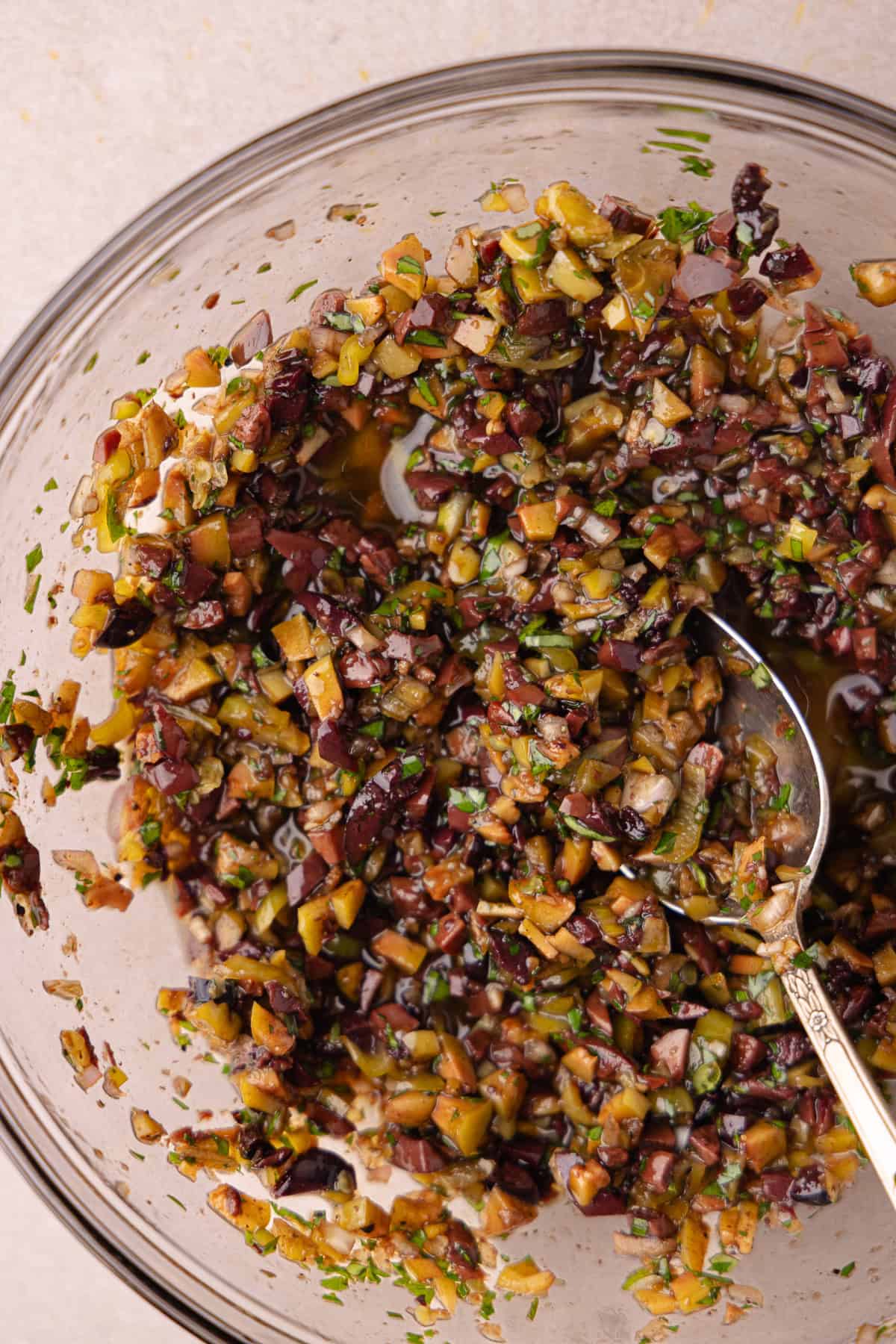 Olive tapenade is mixed together in a small mixing bowl.