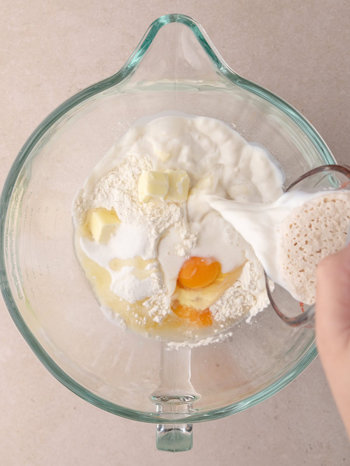 Frothy yeast mixture is added to the brioche dough ingredients sitting stand mixer bowl.