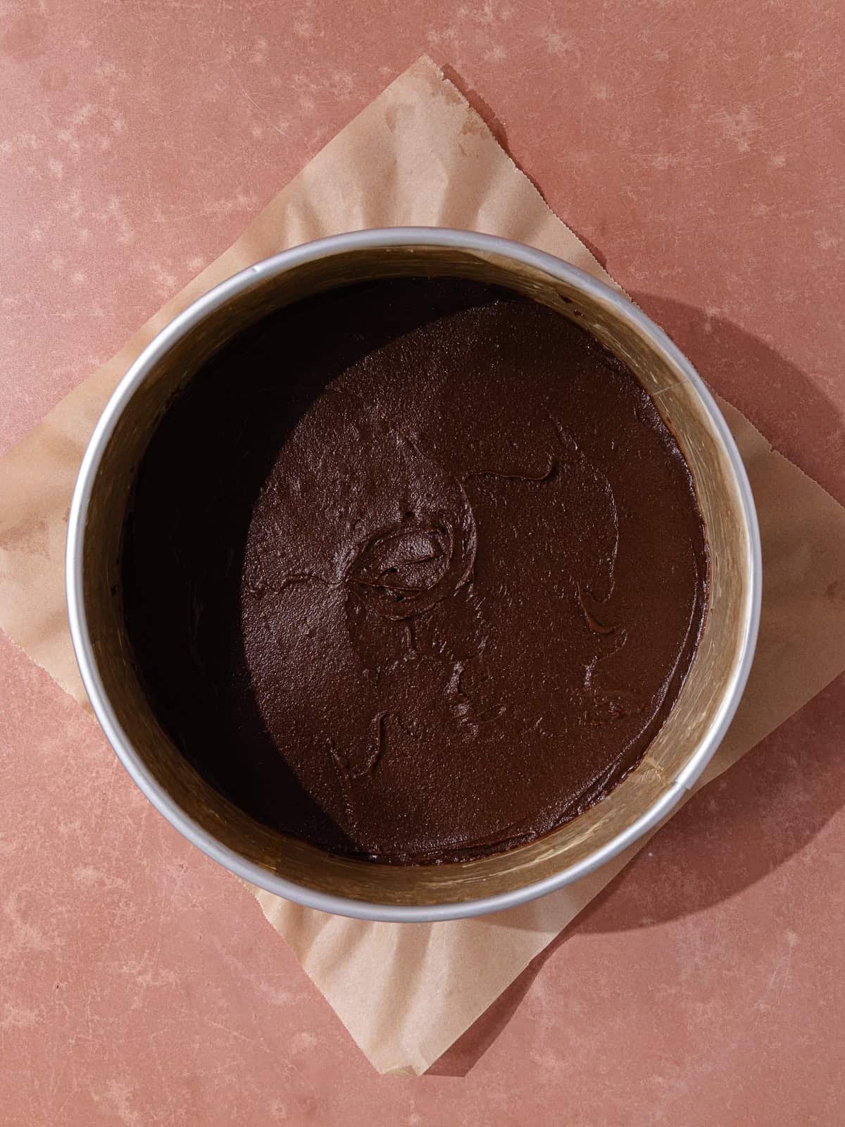 The chocolate cake batter is spread on the bottom of the springform pan.