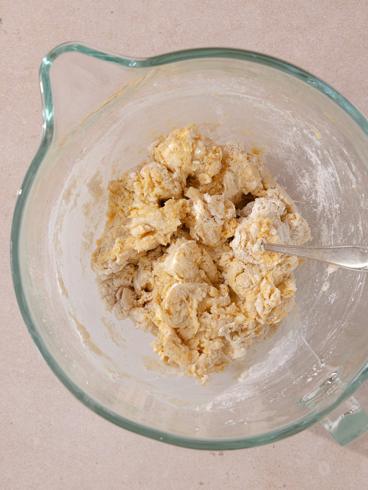 Shaggy ball of dough is in the bowl of a stand mixer.