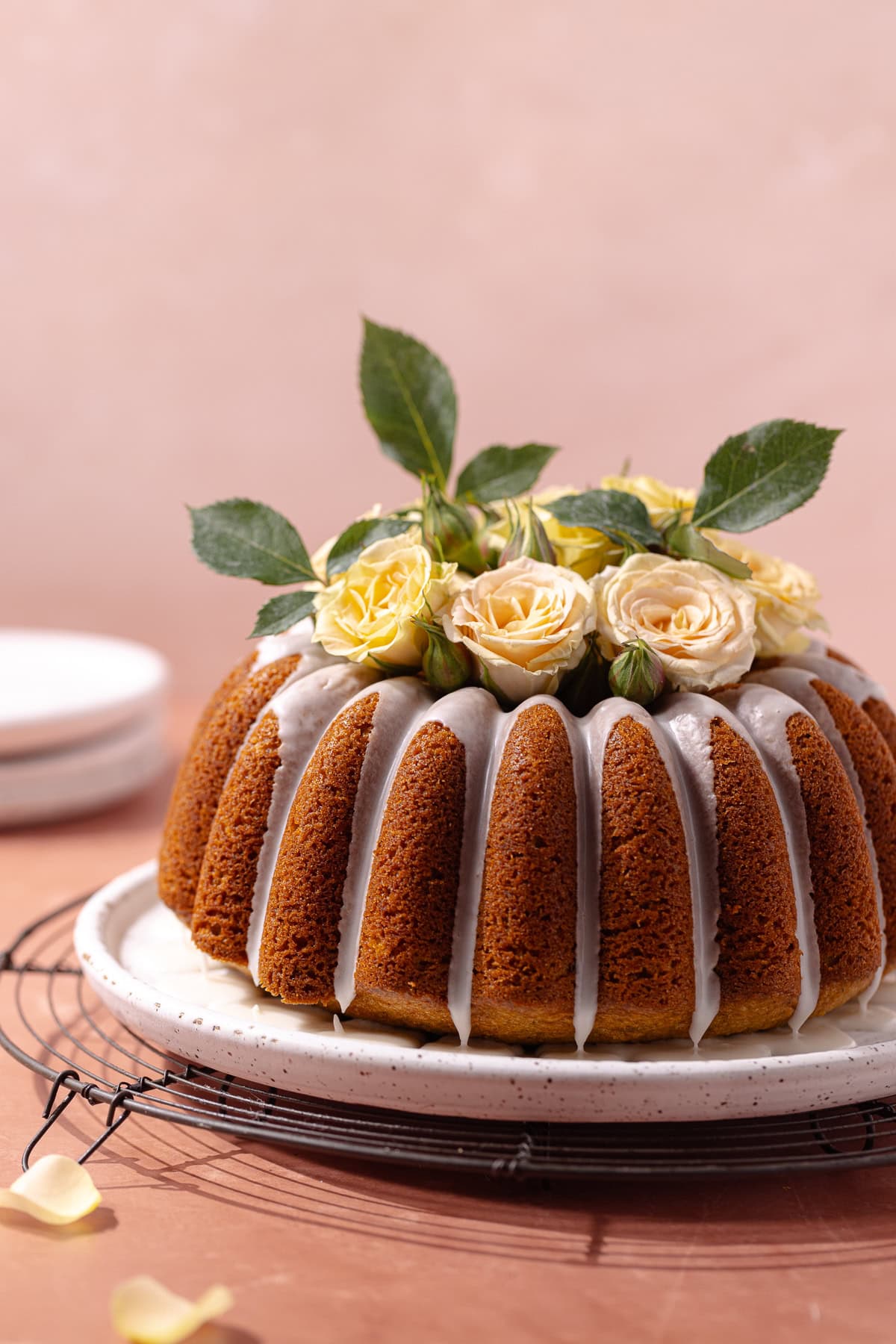 Pistachio rose cardamom olive oil cake with rose water glaze sitting on a serving plate.