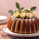 Pistachio rose cardamom olive oil cake with rose water glaze sitting on a serving plate feature photo.