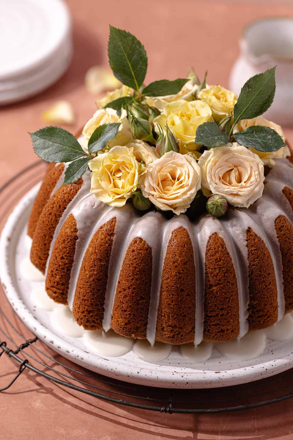 Pistachio rose cardamom olive oil cake with rose water glaze sitting on a serving plate.