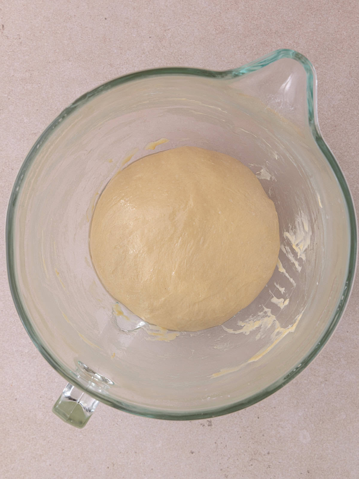 Ball of kneaded dough is sitting in the stand mixer bowl.