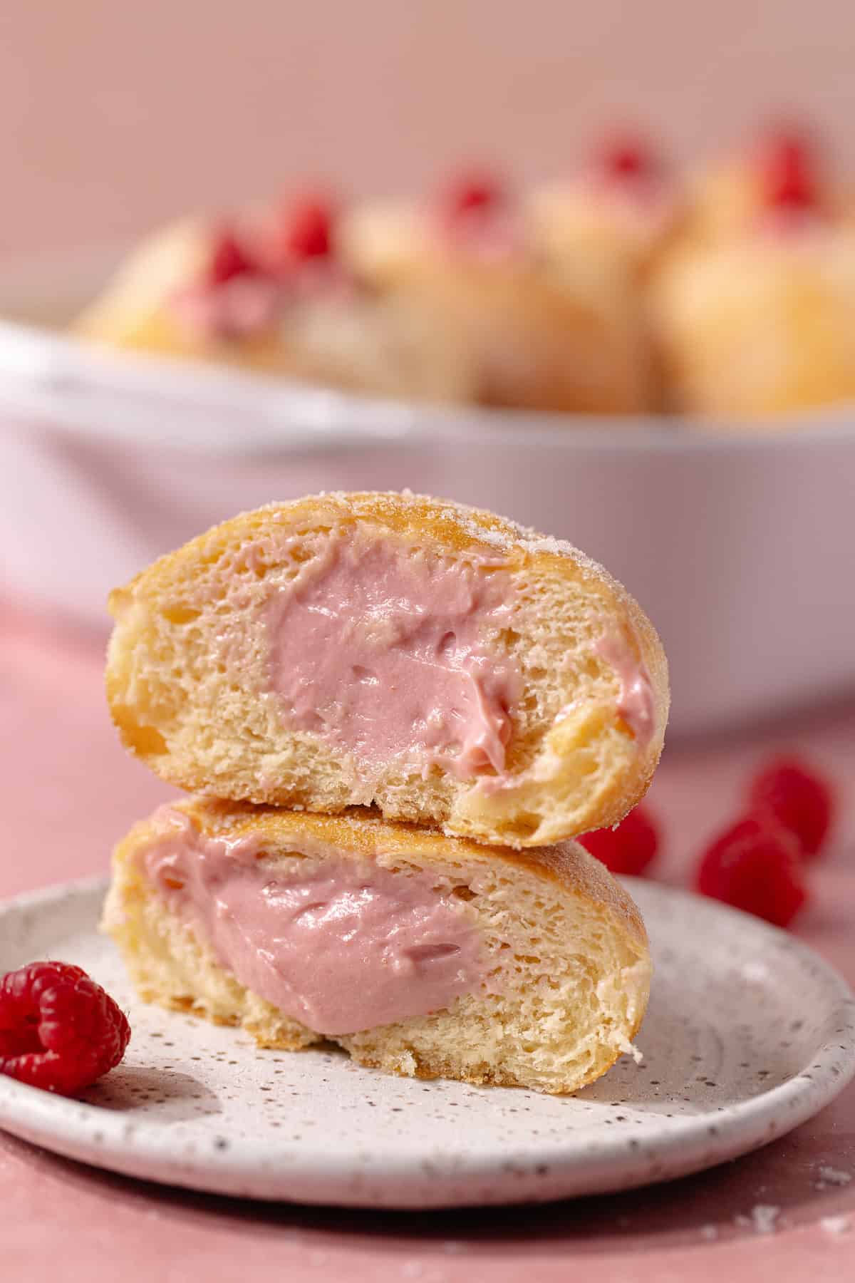 The inside of a Raspberry cheesecake donuts sitting a dessert plate.