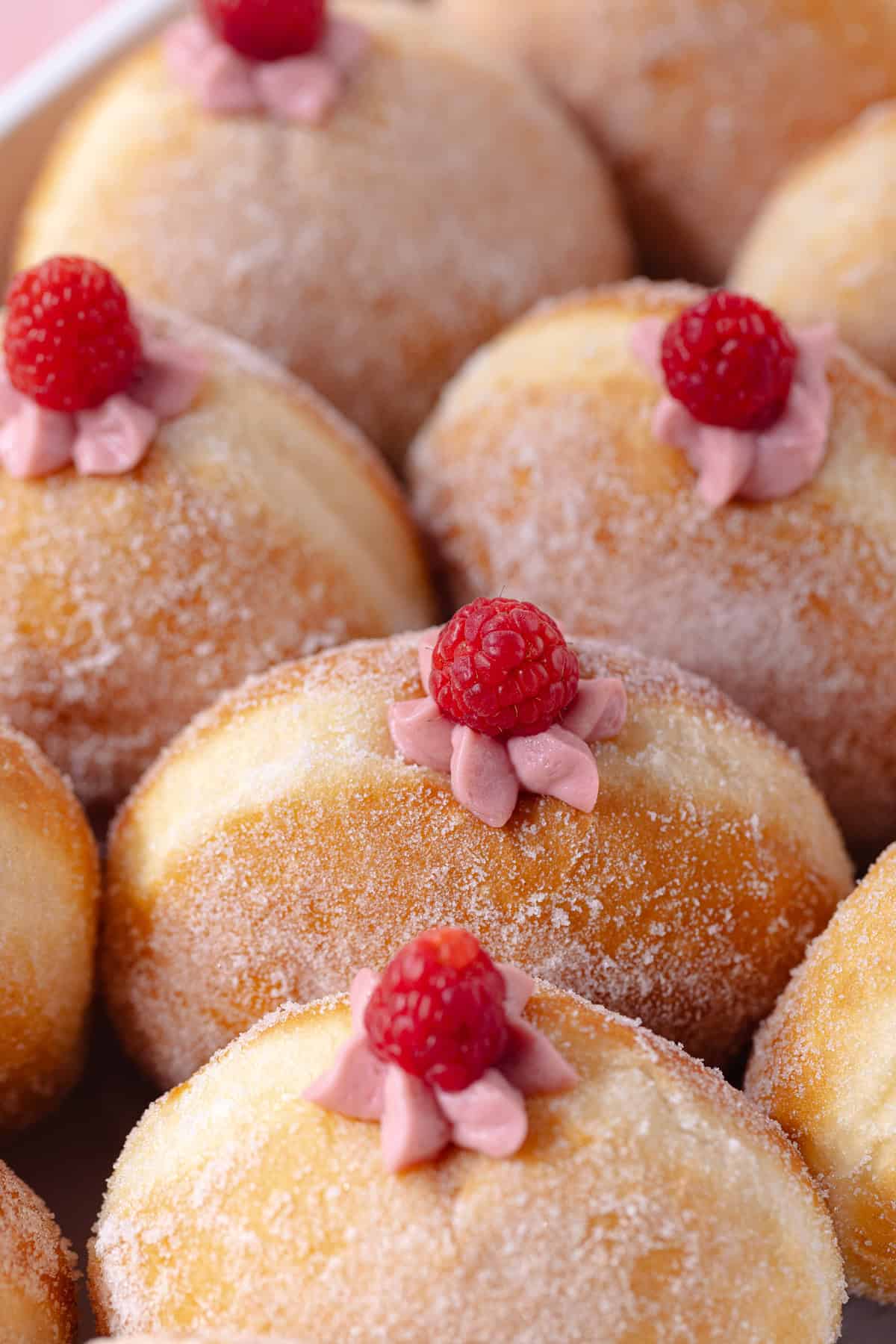 Raspberry cheesecake donuts sitting in a white baking dish.