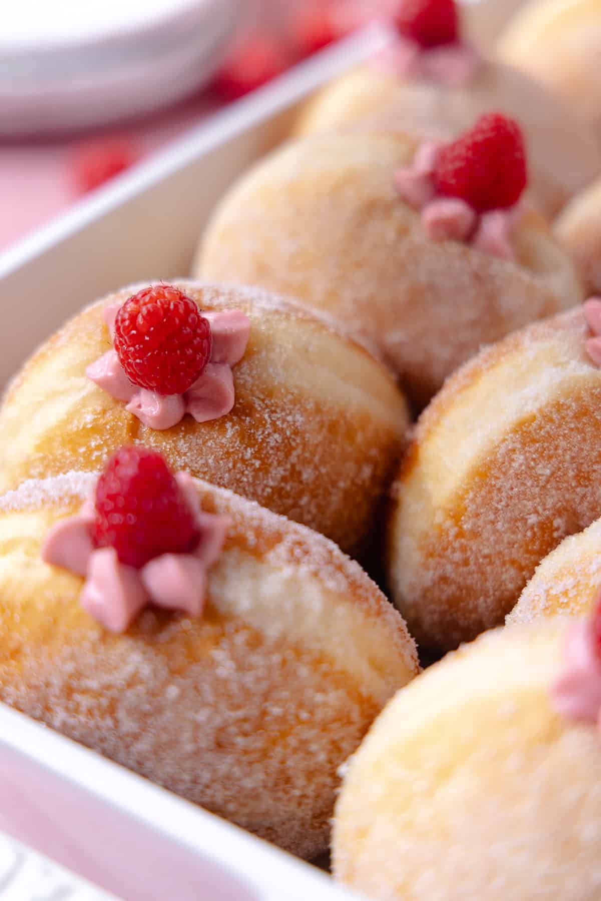 Raspberry cheesecake donuts sitting in a white baking dish.