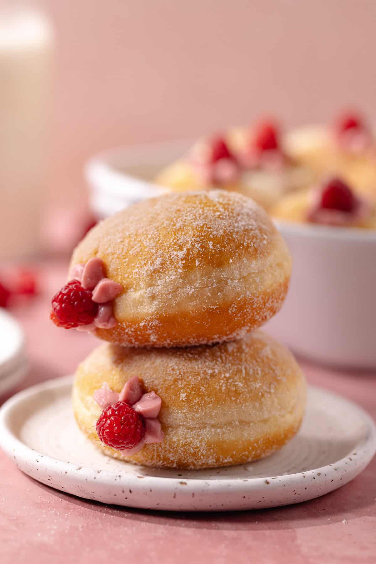 A double stack of raspberry cheesecake donuts sitting on a dessert plate.