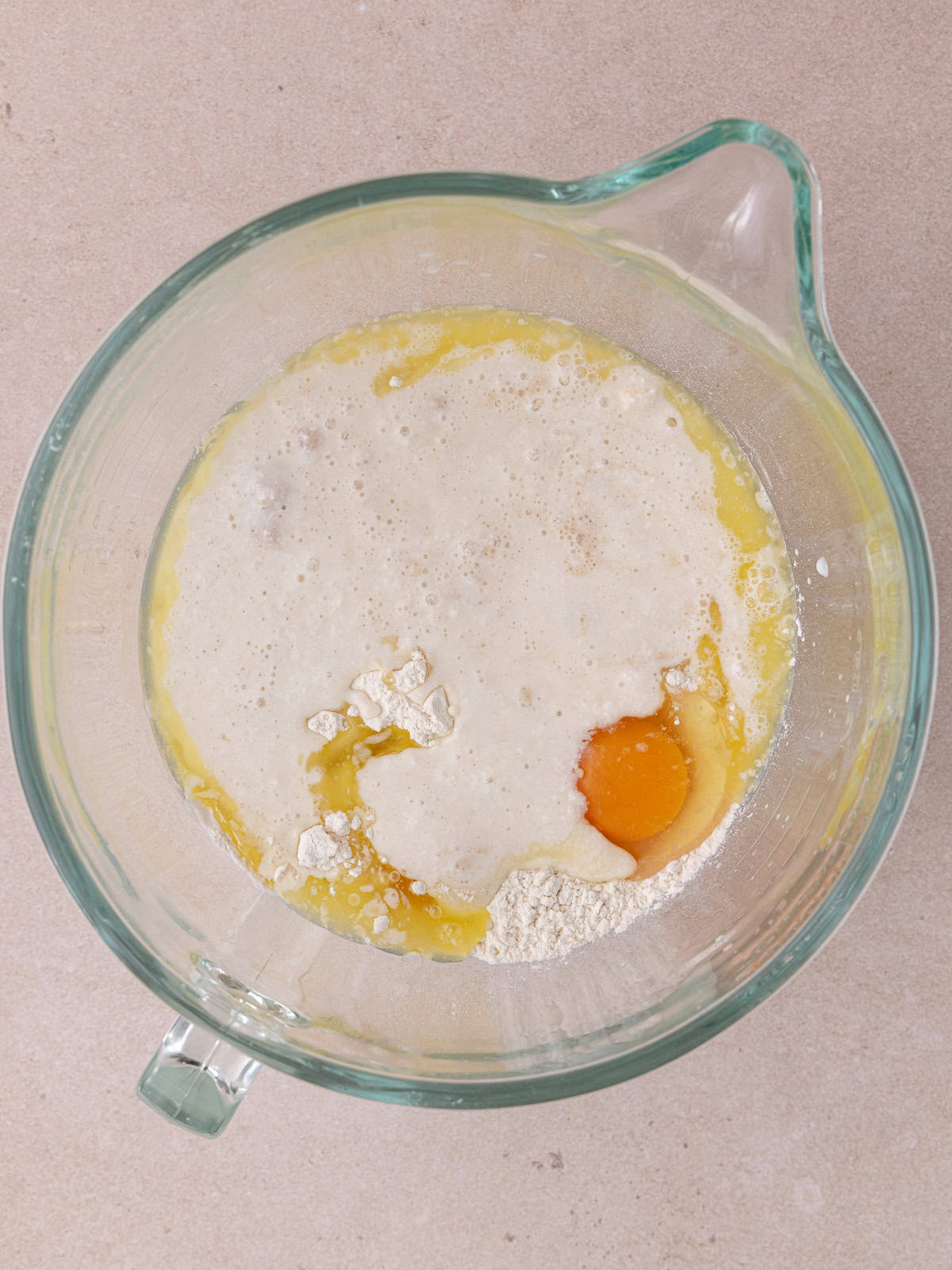 Flour, melted butter, eggs, salt, bloomed yeast mixture, and sugar are in a stand mixer bowl.