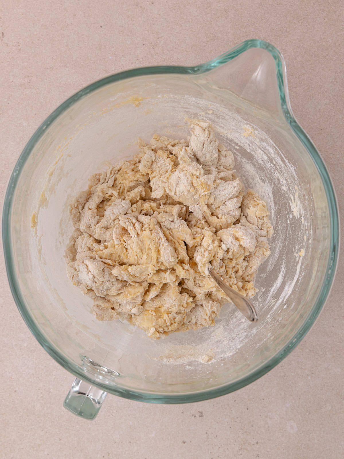 Shaggy ball of dough sits in a glass mixing bowl.