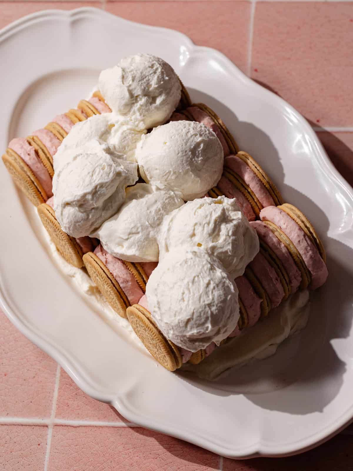 Scoops of whipped cream on top of the assembled cake.