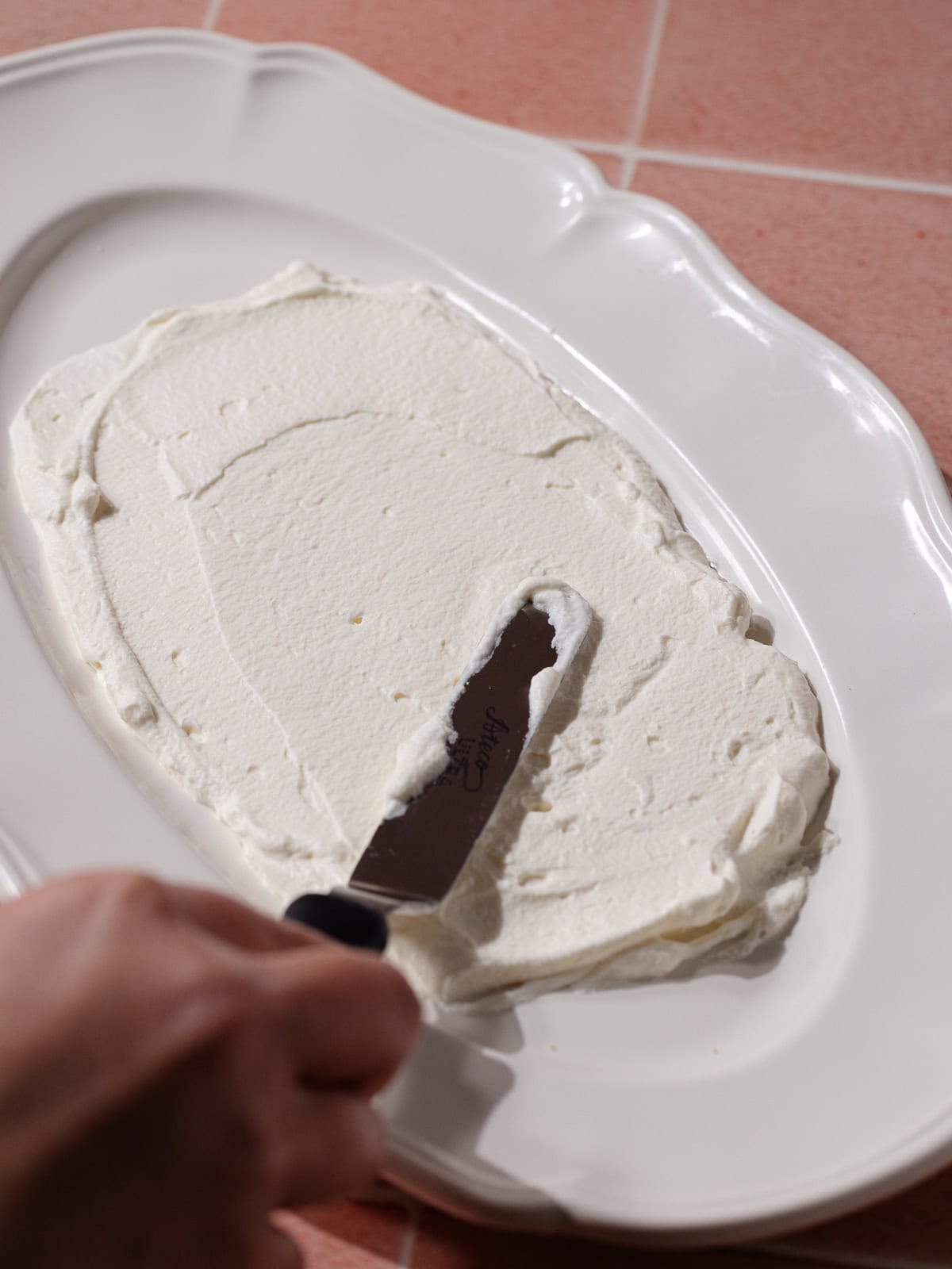 Whipped cream is spread on a long serving plate.