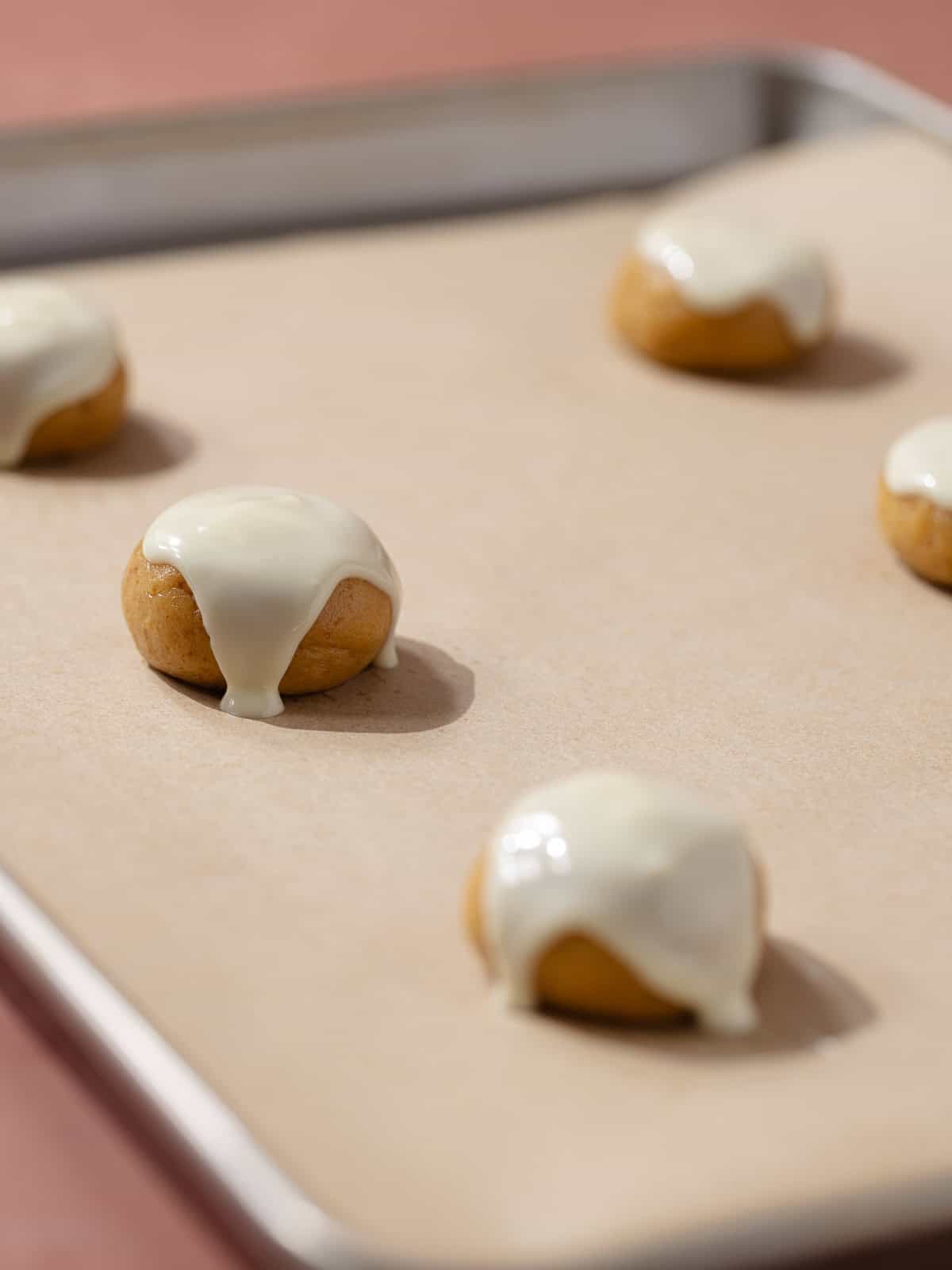 Melted white chocolate is poured over the balls of cookie dough.