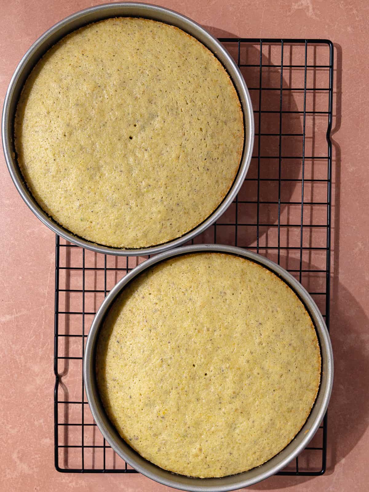 Cakes are baked and sitting in a wire rack.