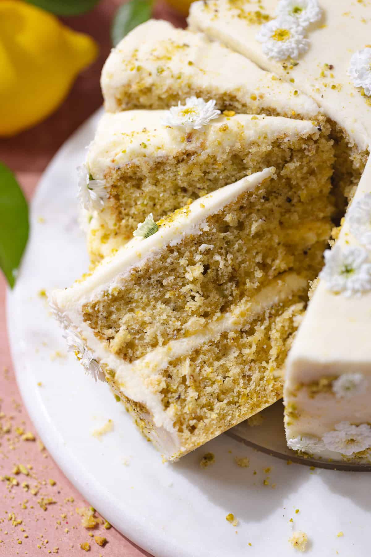 Slices of pistachio lemon cake on a marble serving plate.