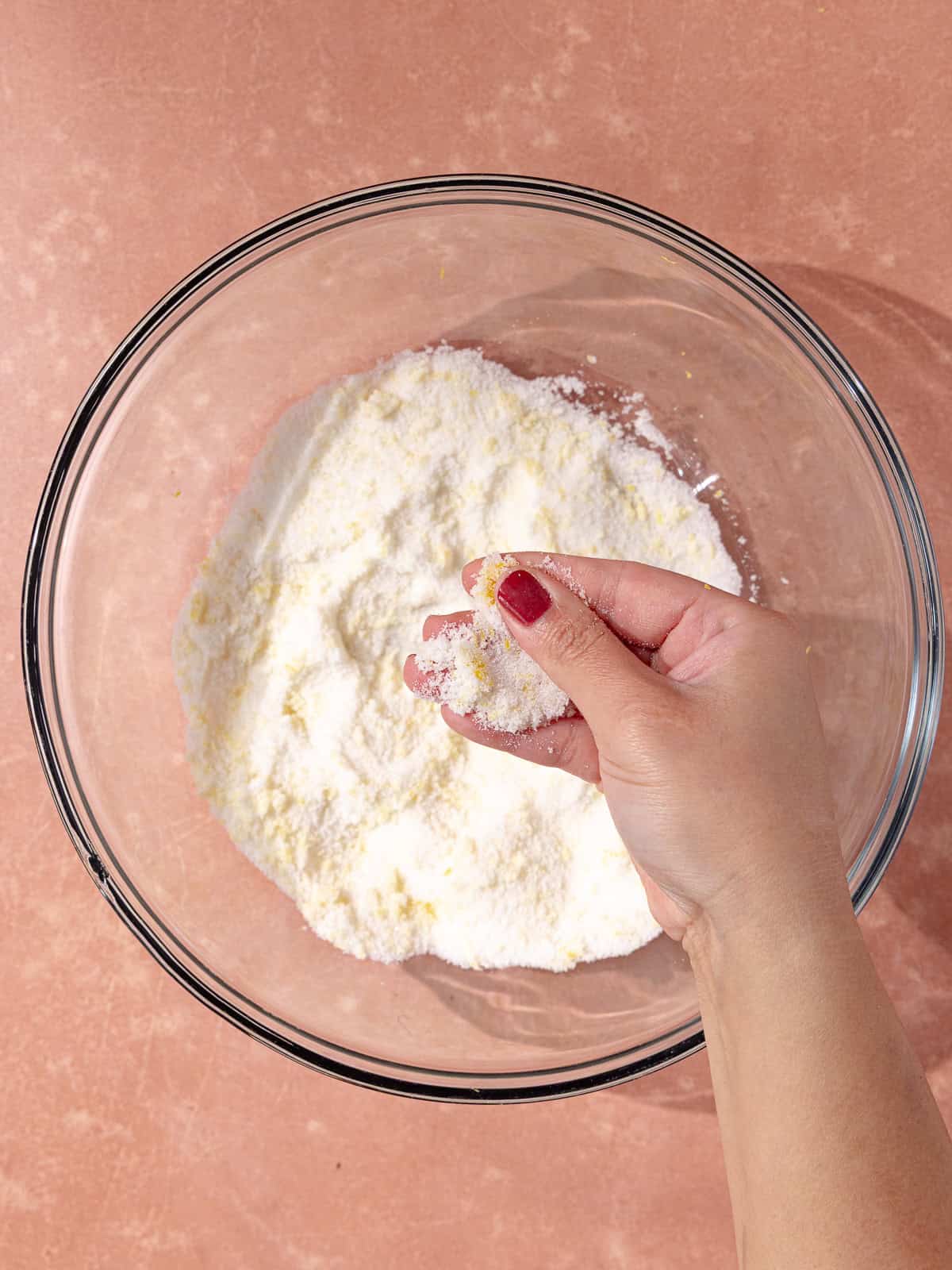 White granulated sugar and finely grated lemon zest is in a large mixing bowl.