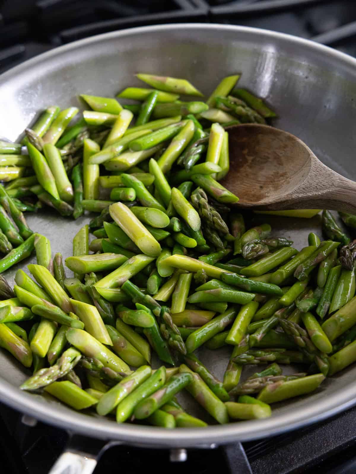 Cut asparagus sauteed in a frying pan.